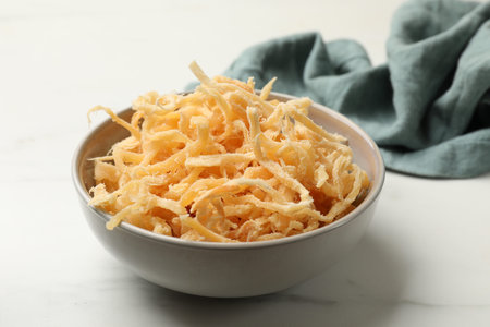 Dried squid shavings in bowl on white marble table, closeup