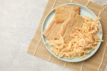 Different tasty dried squid on gray table, top view. Space for text