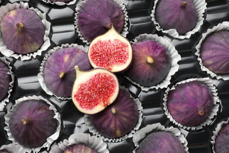 Whole and cut figs in plastic container, top view