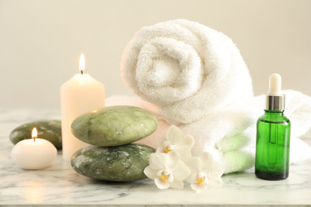 Beautiful spa composition with burning candles on white marble table, closeup
