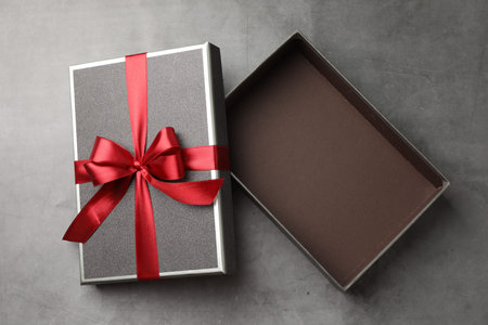 Opened gift box with beautiful lid on gray table, top view