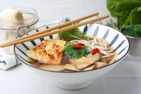 Tasty ramen with king oyster (eryngii) mushrooms in bowl on light table, closeup