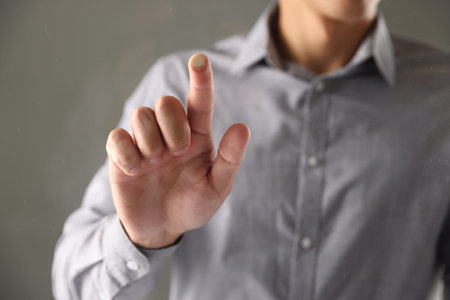 Man touching something on gray background, closeup