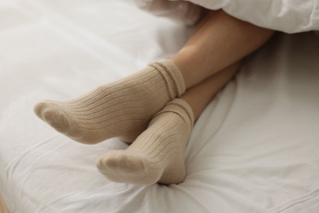 Woman in socks on bed with white lines, closeup