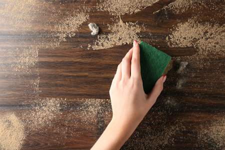 Woman wiping dust off wooden table, top view. Space for text