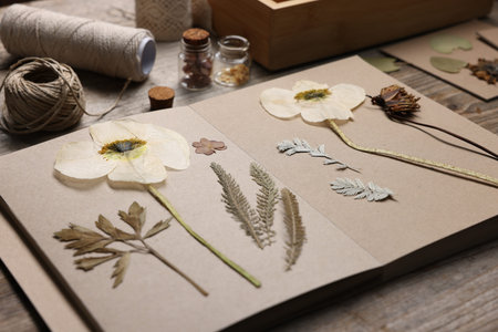 Dry flowers, leaves and notebook on wooden table, closeup