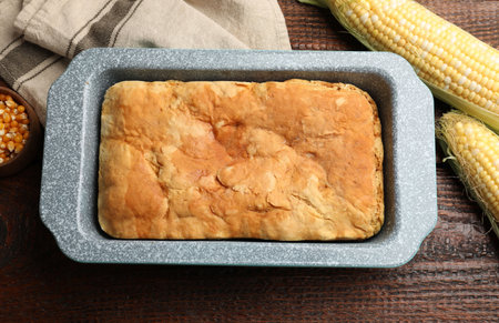 Freshly baked cornbread, seeds and cobs on wooden table, flat lay