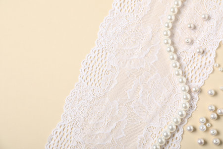 Beautiful pearls and lace fabric on beige background, flat layの写真素材