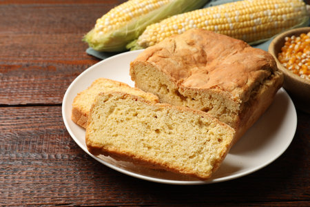 Freshly baked cornbread, cobs and seeds on wooden table, closeup