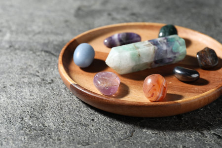 Different beautiful gemstones on gray table, closeup.