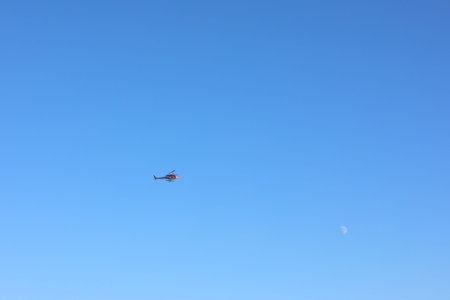 Modern helicopter flying in clear blue sky on sunny day