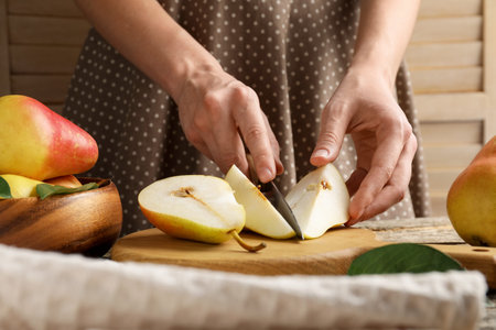 Woman cutting fresh pears at wooden table, closeupの写真素材