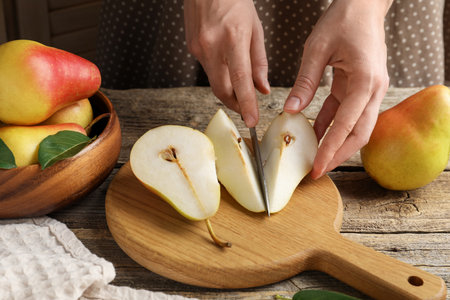 Woman cutting fresh pears at wooden table, closeupの写真素材