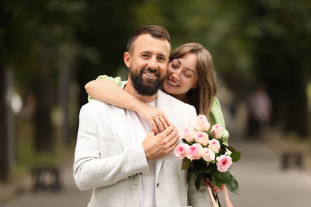 Making marriage proposal. Woman with engagement ring, flowers and her happy fiance outdoors