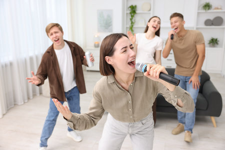 Young woman singing karaoke with friends at home, selective focusの写真素材
