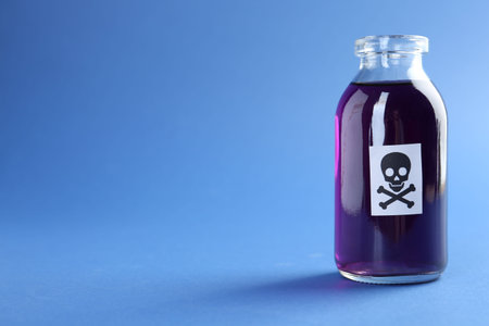 Bottle of poison with warning sign on light blue background, closeup. Space for textの写真素材