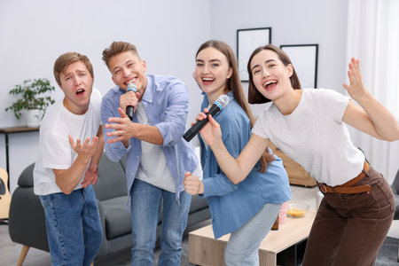 Group of friends singing karaoke at homeの写真素材
