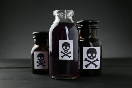 Bottles with warning signs on black wooden table, closeupの写真素材