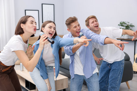 Group of friends singing karaoke at homeの写真素材