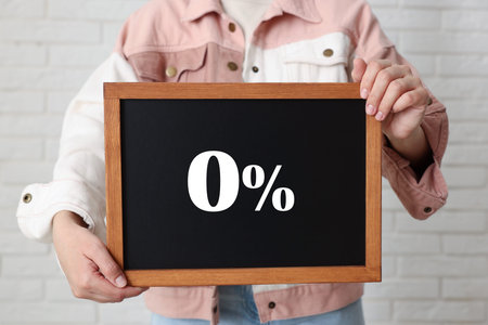 Woman holding chalkboard with 0% indoors, closeup