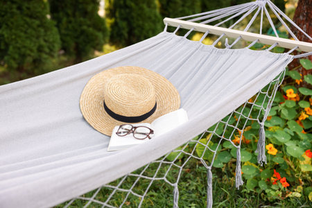 Straw hat, glasses and book on hammock outdoorsの写真素材