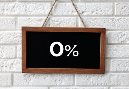 Chalkboard with 0% hanging on white brick wall