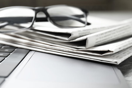 Newspapers, laptop and glasses on table, closeupの写真素材
