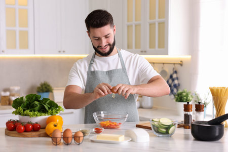 Smiling man cooking at table in kitchen