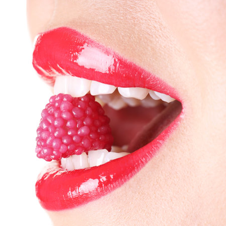 Woman with red lipstick on her lips and raspberry candy against white background, closeup
