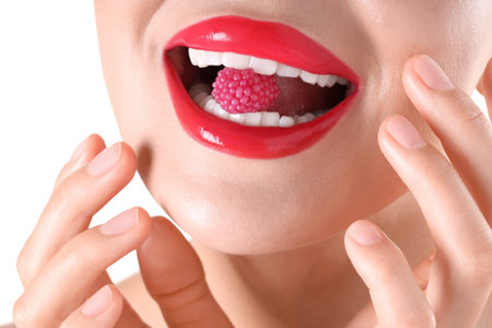 Woman with red lipstick on her lips and raspberry candy against white background, closeup