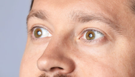 Man with beautiful eyes on light grey background, closeup