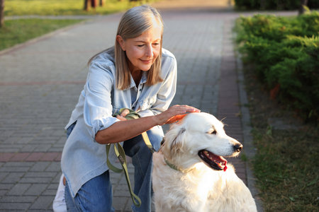 Senior woman with adorable Golden Retriever dog outdoorsのeditorial素材