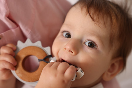 Mother with her cute baby biting teether toy at home, closeupの写真素材