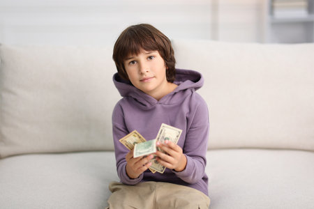 Boy with pocket money on sofa at homeの写真素材