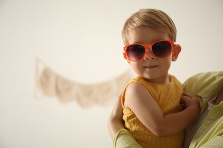 Mother with her baby wearing sunglasses at home, closeup. Space for textの写真素材