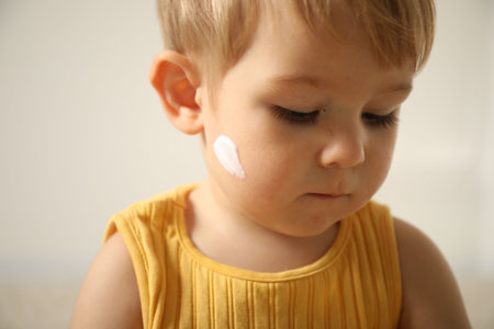 Cute baby with cream on his face at home, closeupの写真素材
