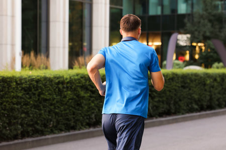 Man in sportswear running outdoors, back view