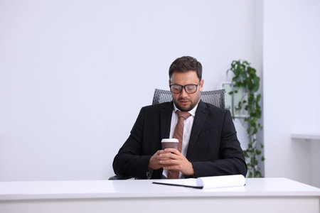 Air conditioning. Man with cup of hot drink suffering from cold temperature at workplace in officeの写真素材