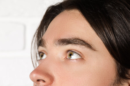 Man with beautiful eyes on blurred light background, closeup