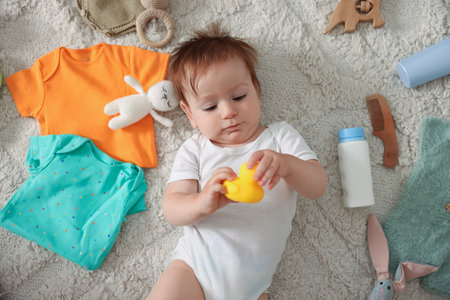 Cute baby, different clothes and accessories on floor, top view