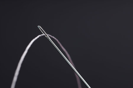 Sewing needle with thread on black background, macro view. Space for textの写真素材