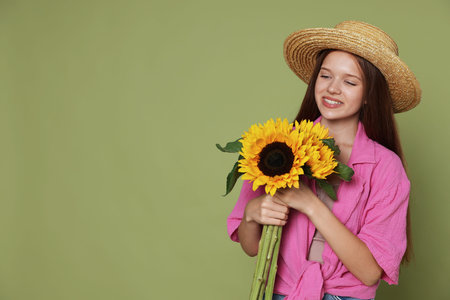 Teenage girl with beautiful sunflowers on green background, space for textの写真素材