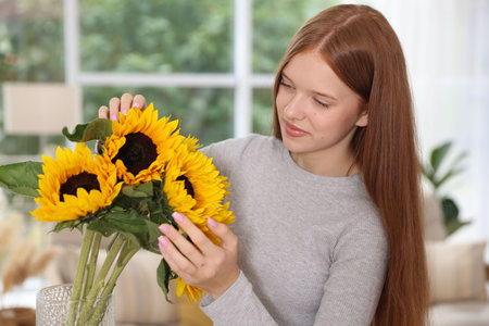 Teenage girl with beautiful sunflowers at homeの写真素材