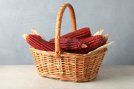 Ripe red corn cobs in basket on light table