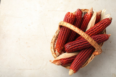 Ripe red corn cobs in basket on light table, top view. Space for textの写真素材