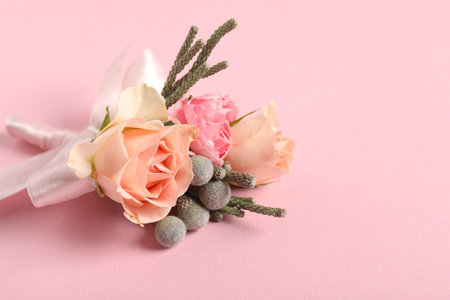 Boutonniere with beautiful flowers on light pink background, closeup. Space for text