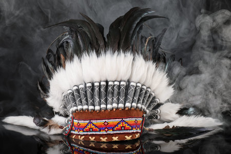 Traditional warbonnet (Native American chief headdress) in smoke on black mirror surface