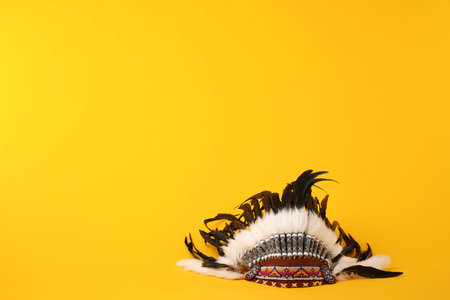 Traditional warbonnet (Native American chief headdress) on yellow background. Space for text