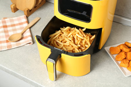 Air fryer with cooked fries and chicken nuggets on counter