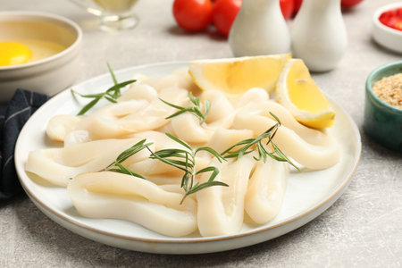 Uncooked squid rings and ingredients on gray table, closeup